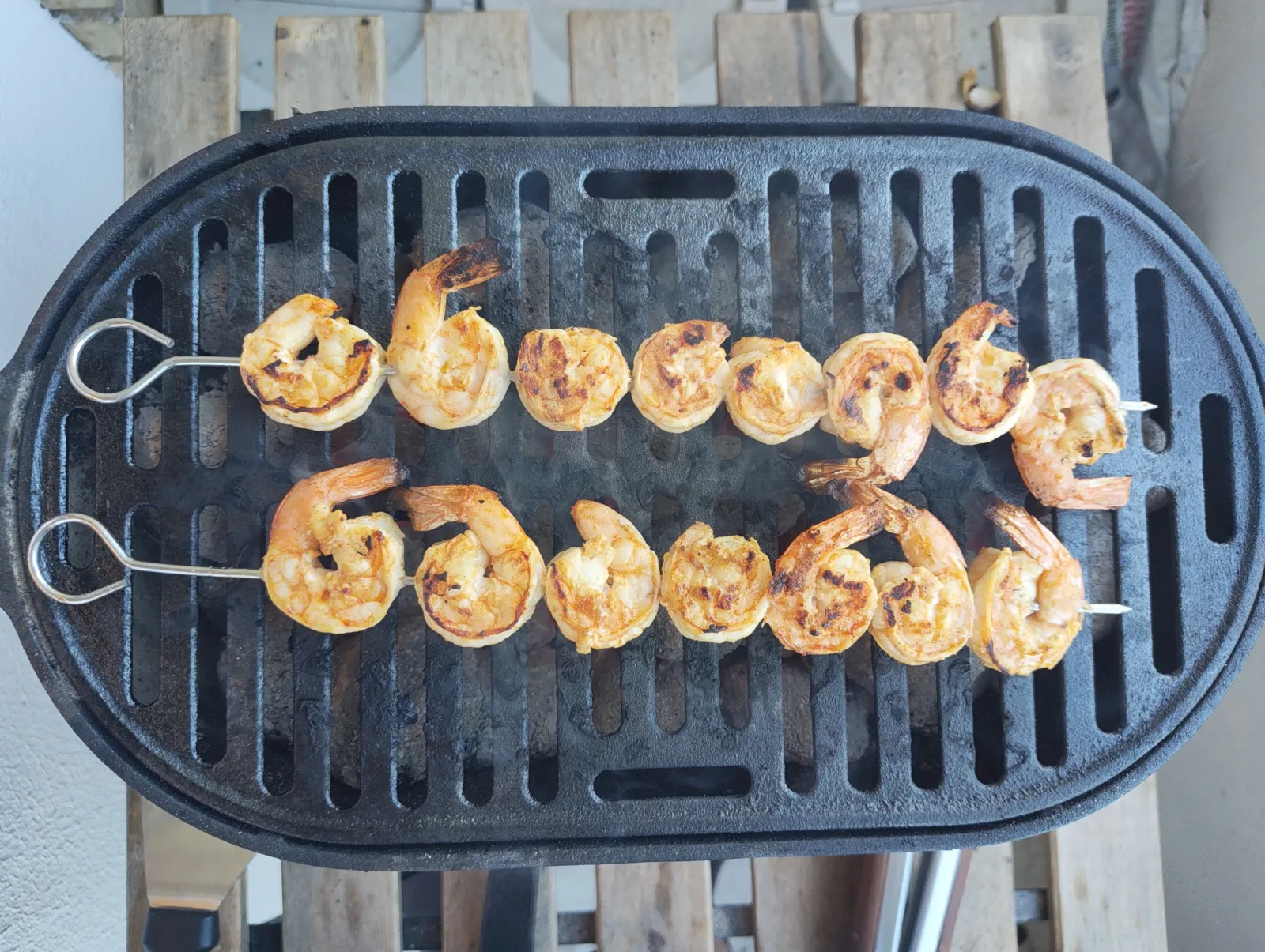 a grill showing the marinated skewers of shrimp